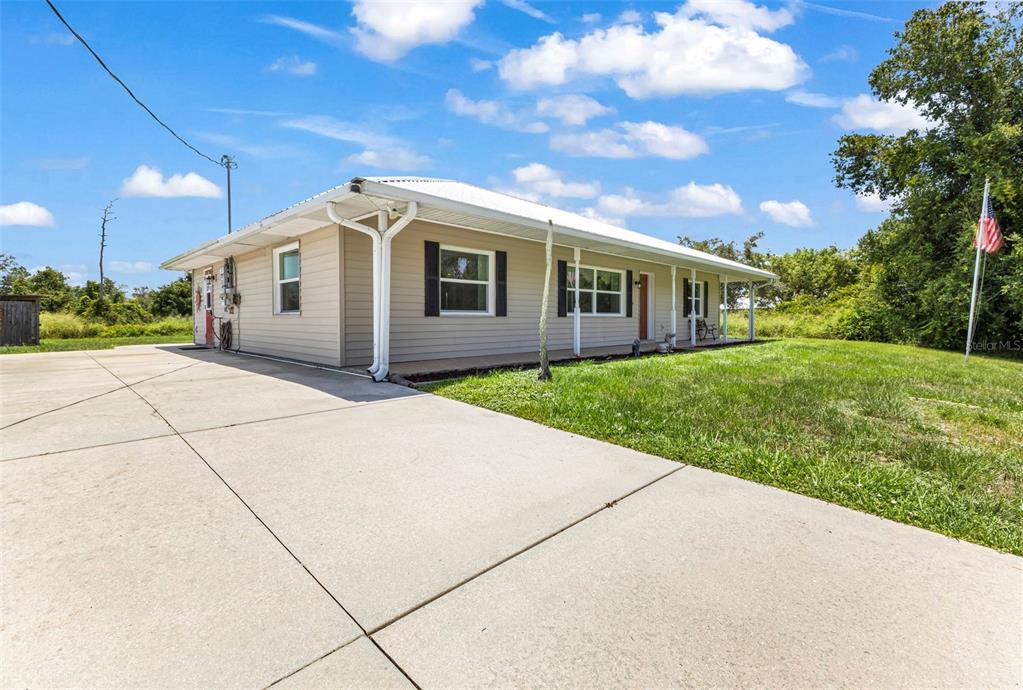 A single-story house with tan siding and a concrete driveway under a blue sky — 30 SUCCESS DRIVE, PUNTA GORDA, FL