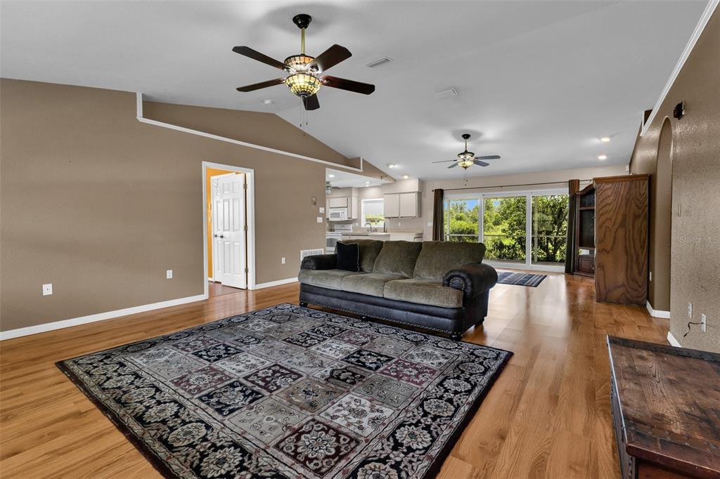 A living room features hardwood floors, a large patterned rug, a sofa, and ceiling fans — 30 SUCCESS DRIVE, PUNTA GORDA, FL