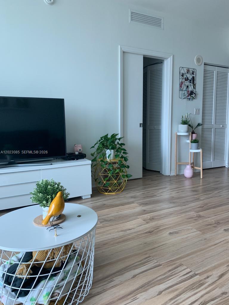 A living room features a television on a white stand, a coffee table, and plants — 951 Brickell Ave # 1503, Miami FL 33131, MIAMI, FL