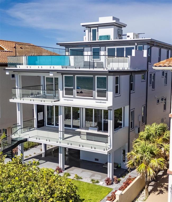An exterior view of a multi-story modern house featuring glass balconies and a rooftop pool — 9600 W GULF BOULEVARD, TREASURE ISLAND, FL