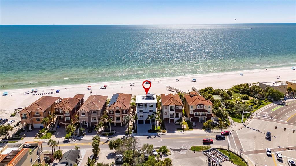An aerial view shows a multi-story house on a beach with a red location pin — 9600 W GULF BOULEVARD, TREASURE ISLAND, FL