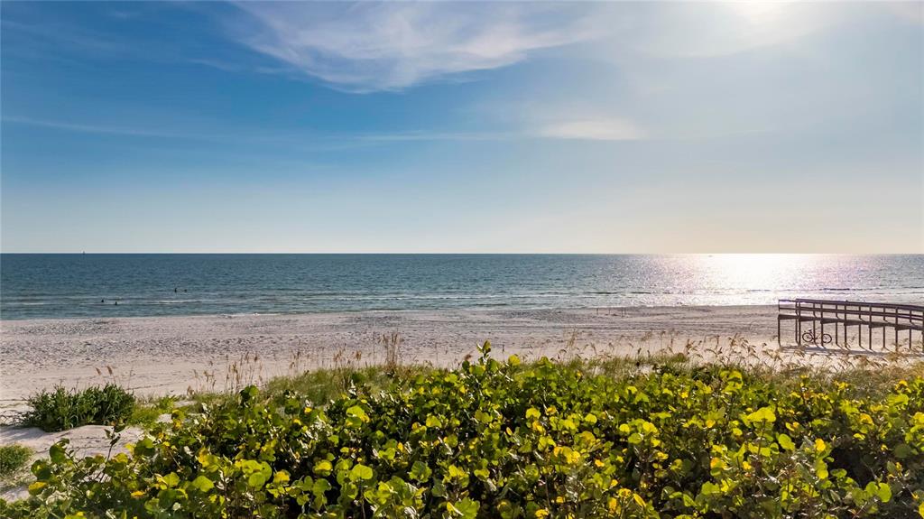 A sandy beach with dunes and a wooden walkway overlooks the ocean under a sunny sky — 9600 W GULF BOULEVARD, TREASURE ISLAND, FL