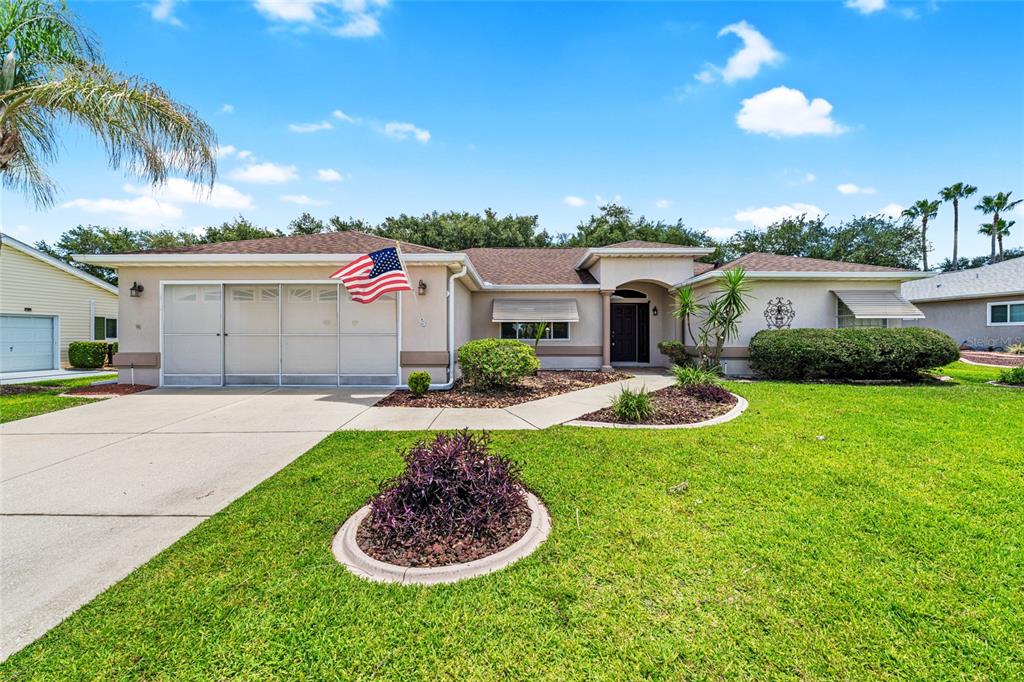 A single-story house with a tan exterior, a garage, and a front lawn — 9082 SE 135TH LOOP, SUMMERFIELD, FL