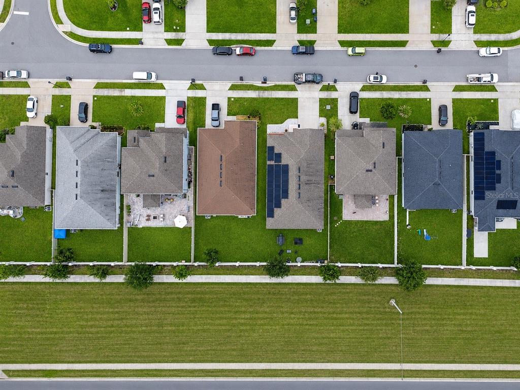 An aerial view shows a row of suburban houses with backyards facing a green field — 2975 PARKFIELD ROAD, ST CLOUD, FL