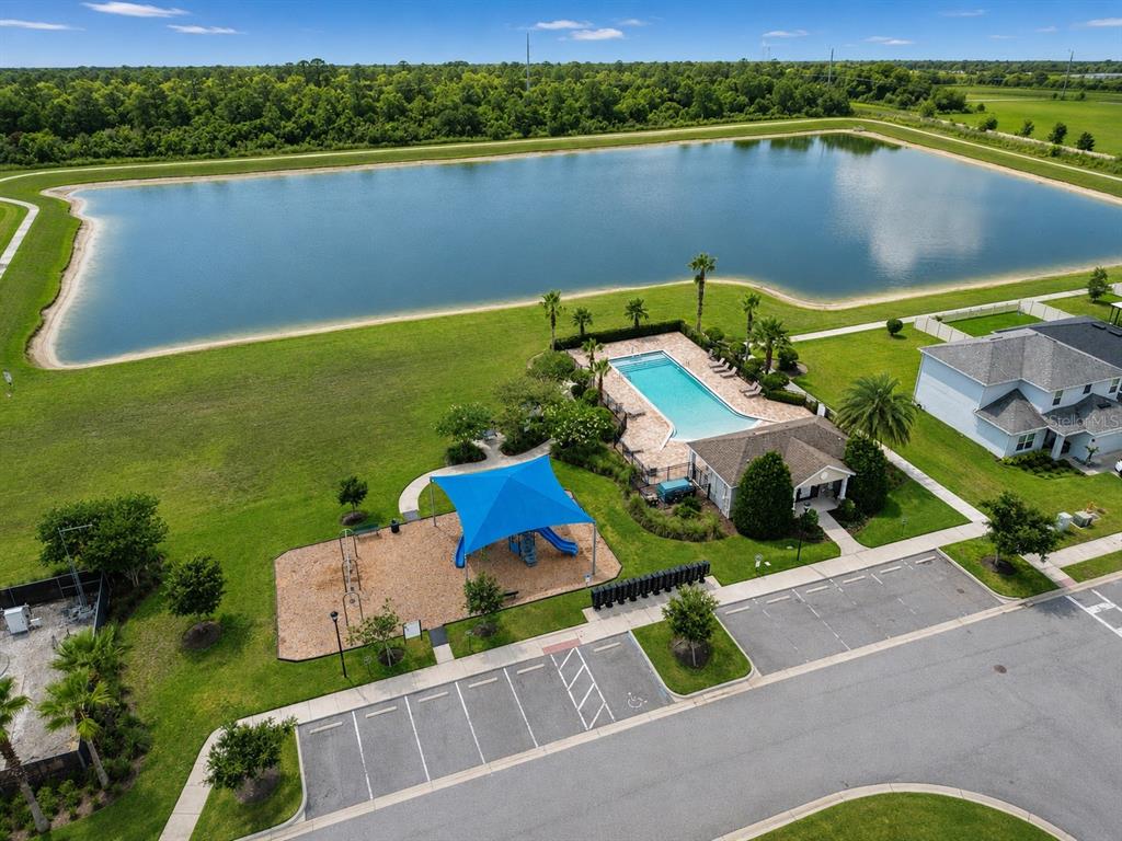 An aerial view of a community pool, playground, and parking lot next to a large pond — 2975 PARKFIELD ROAD, ST CLOUD, FL