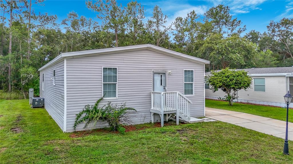 A light gray vinyl-sided mobile home with a small white front porch and stairs — 2908 KINGSWOOD CIRCLE, BROOKSVILLE, FL