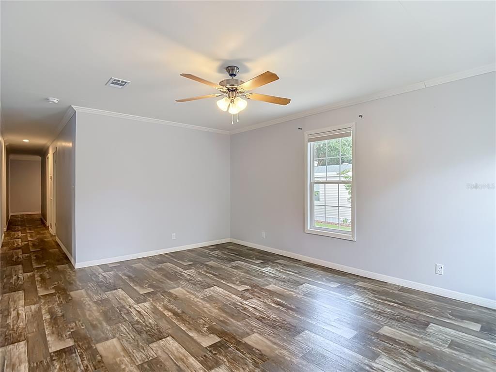 An empty room features light gray walls, wood-look plank flooring, and a ceiling fan — 2908 KINGSWOOD CIRCLE, BROOKSVILLE, FL