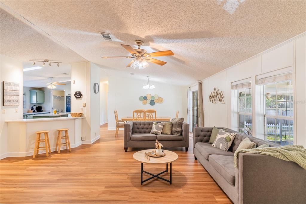 A living room with wood-look flooring, two gray sofas, and an open kitchen area — 5028 CLEWIS AVENUE, TAMPA, FL