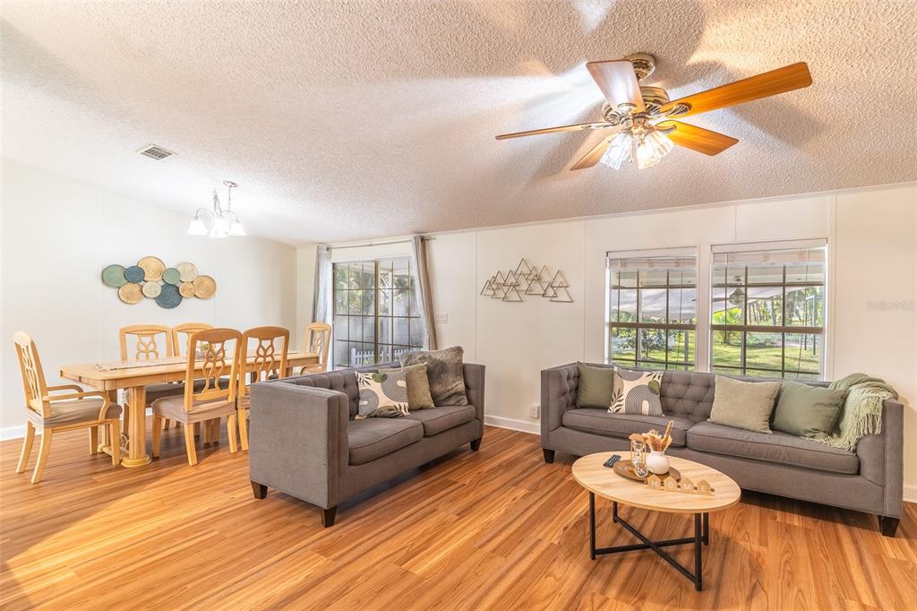 A living and dining area with wood-look flooring, two grey sofas, and a dining table — 5028 CLEWIS AVENUE, TAMPA, FL