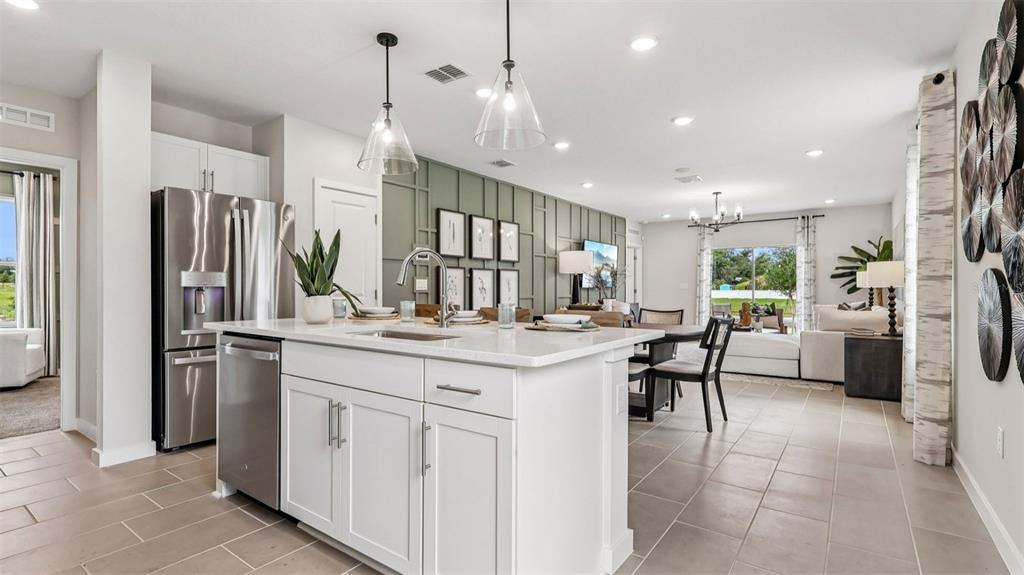 A kitchen with a white island and stainless steel appliances opens into a living area — 428 LIBERTY BEND, HAINES CITY, FL
