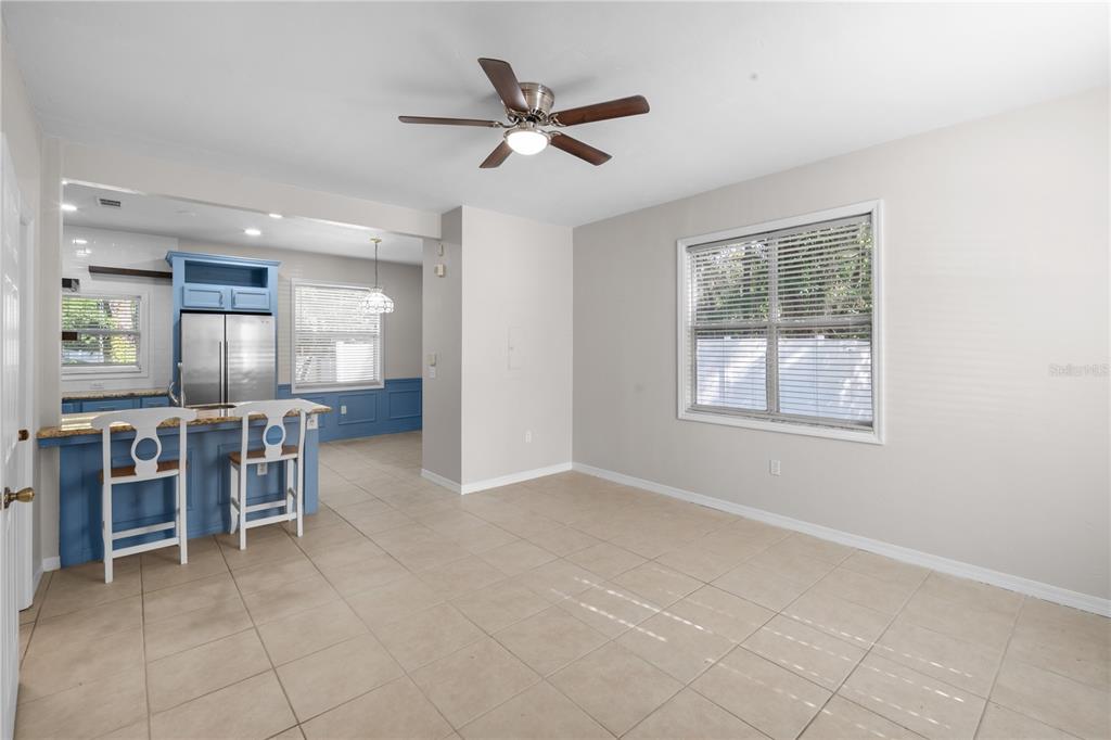 A dining area with tile floors and a ceiling fan opens to a blue kitchen — 1710 NW 7TH STREET UNIT 404, GAINESVILLE, FL