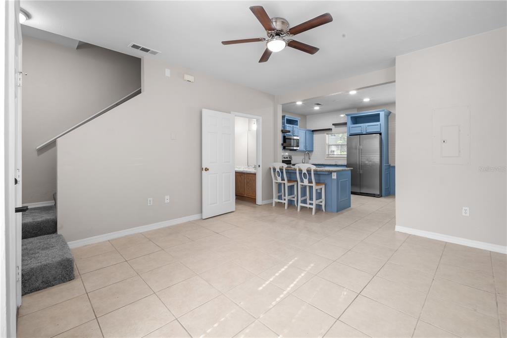 A living room with a beige sofa and wooden coffee table opens to a blue kitchen — 1710 NW 7TH STREET UNIT 404, GAINESVILLE, FL