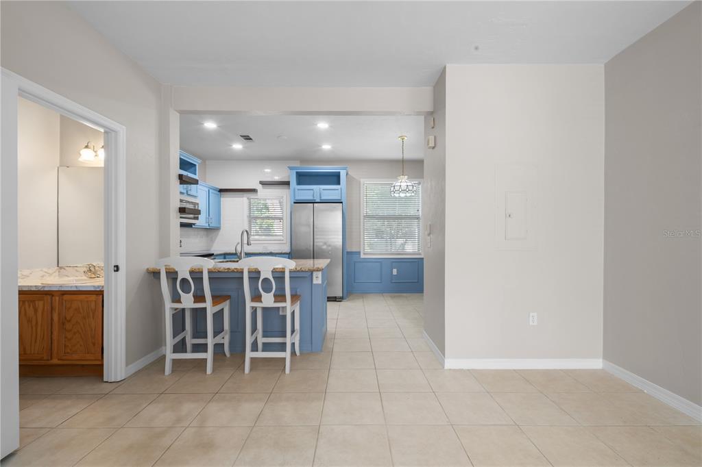 An open-concept living area with tile flooring, a staircase, a bathroom, and a blue kitchen — 1710 NW 7TH STREET UNIT 404, GAINESVILLE, FL