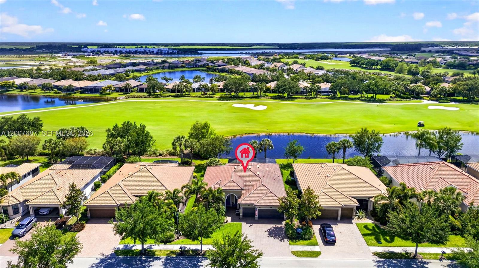 A kitchen with white cabinets, a large island with blue stools, and hardwood flooring — 6120 Victory Dr, Ave Maria FL 34142, AVE MARIA, FL