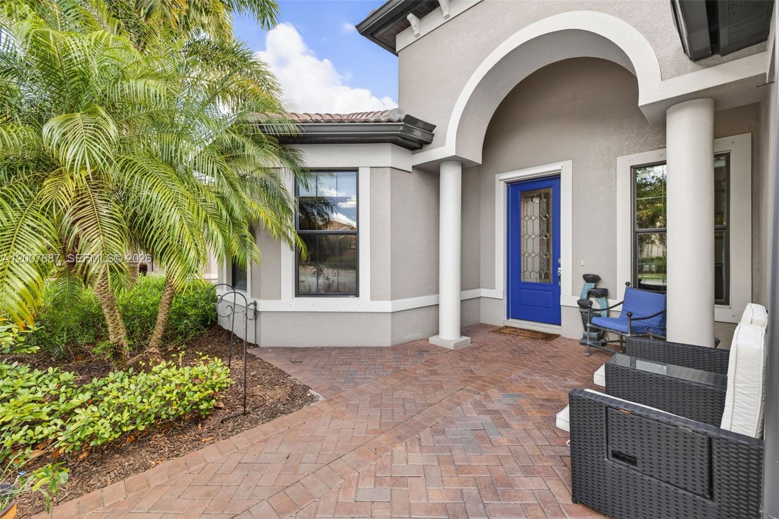 An open-concept living room and kitchen featuring gray sofas, a red rug, and white cabinetry — 6120 Victory Dr, Ave Maria FL 34142, AVE MARIA, FL