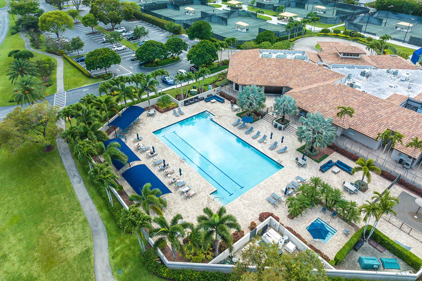 A screened-in balcony features wicker patio furniture, tile flooring, and a view of neighboring buildings — 6626 Via Regina, Boca Raton FL 33433, BOCA RATON, FL