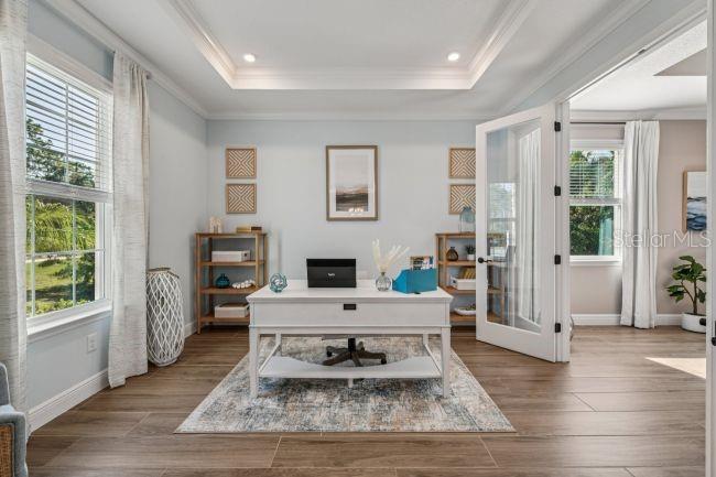 A home office features a white desk, wood-look tile floors, and glass-paneled double doors — 16907 ROYAL PALM DRIVE, GROVELAND, FL
