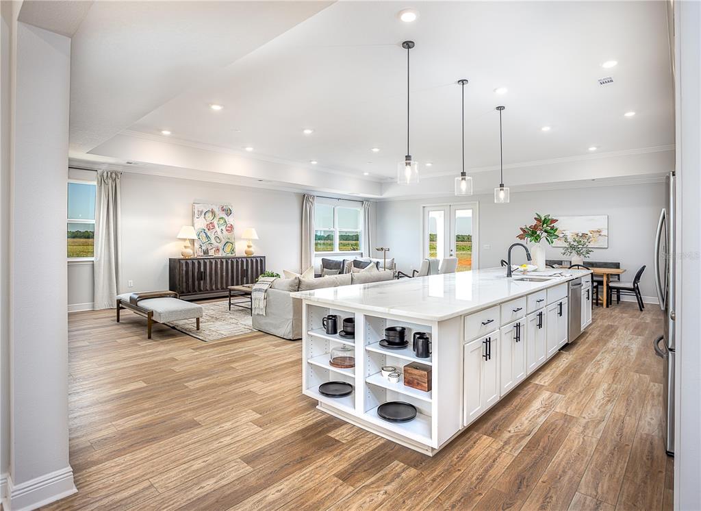An open-concept kitchen with a large white island overlooks a living area and dining space — 16907 ROYAL PALM DRIVE, GROVELAND, FL