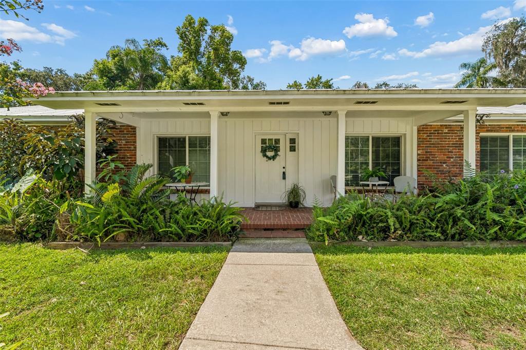 A single-story house with a white front door, brick accents, and a covered porch — 909 TOMLINSON DRIVE, LUTZ, FL