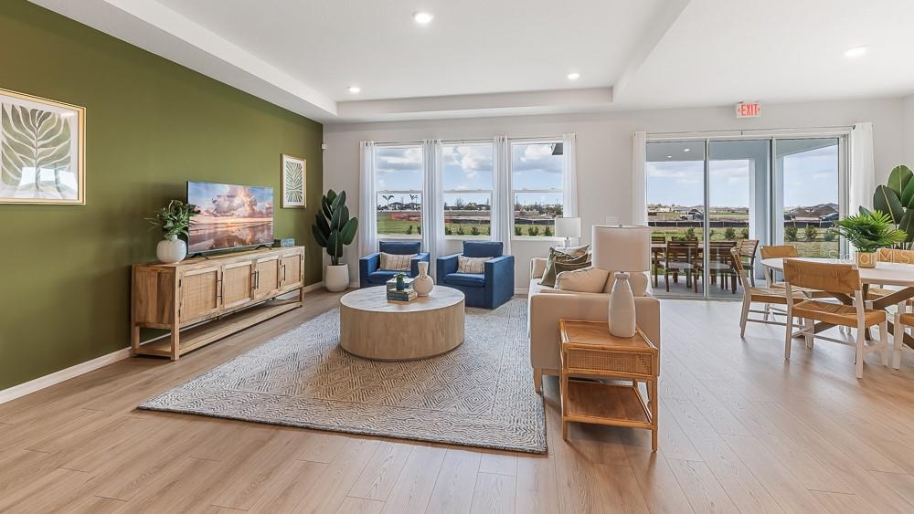 A living room features a green accent wall, light wood flooring, and a sliding glass door — 18241 GANDER TERRACE, LAKEWOOD RANCH, FL