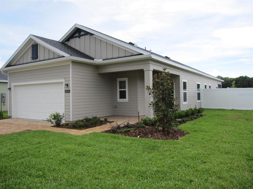 A single-story house with beige horizontal siding, a two-car garage, and a covered porch — 4494 NW 14TH LOOP, OCALA, FL