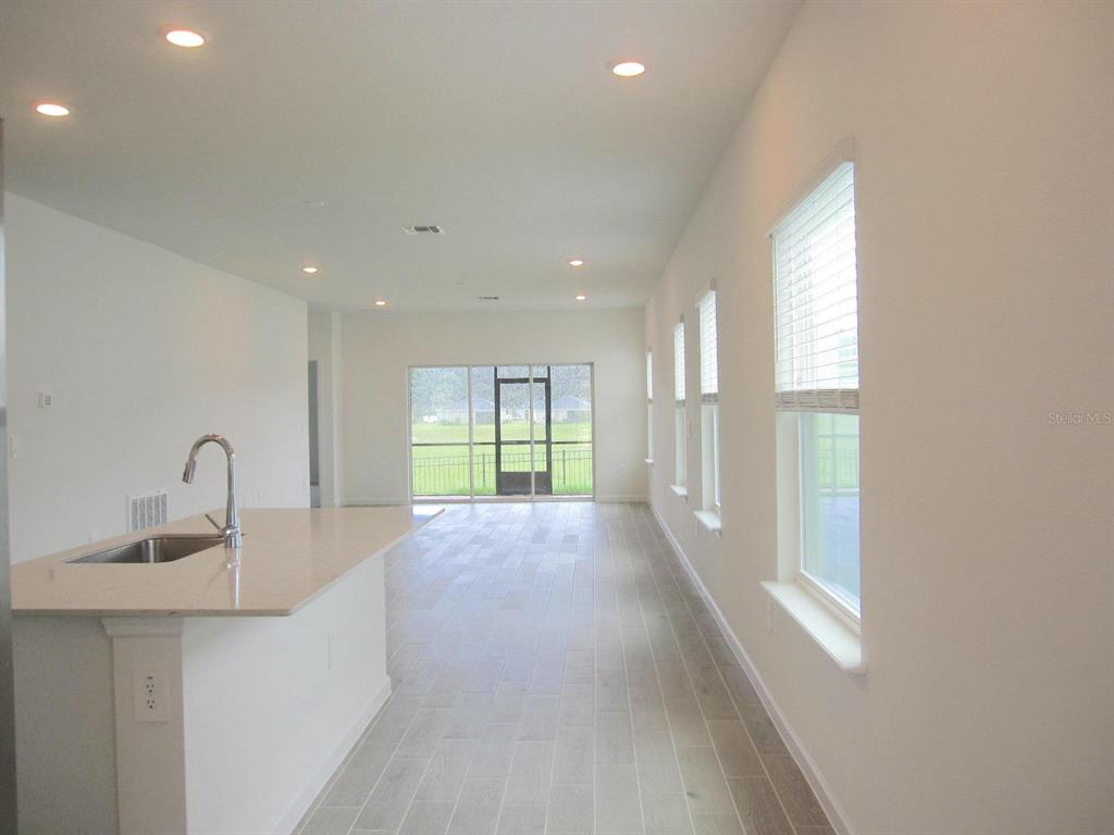 A kitchen island with a sink overlooks an open living area with large windows — 4494 NW 14TH LOOP, OCALA, FL