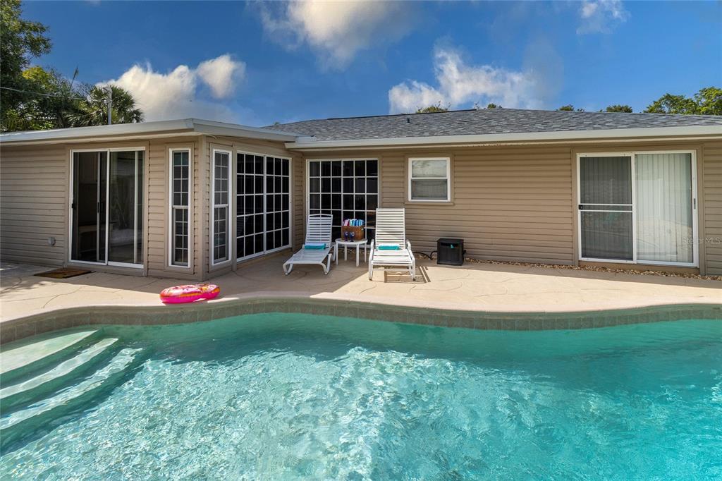 A beige house exterior features a swimming pool, patio, and two lounge chairs — 2865 POPLAR STREET, SARASOTA, FL