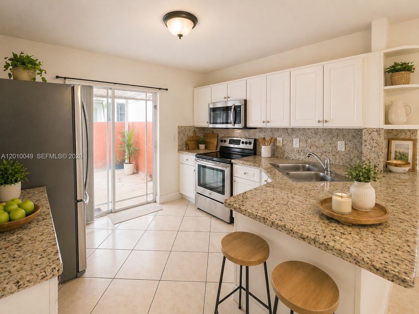 A kitchen features white cabinets, granite countertops, stainless steel appliances, and a sliding glass door — 11051 W Okeechobee Rd # 101, Miami FL 33018, MIAMI, FL