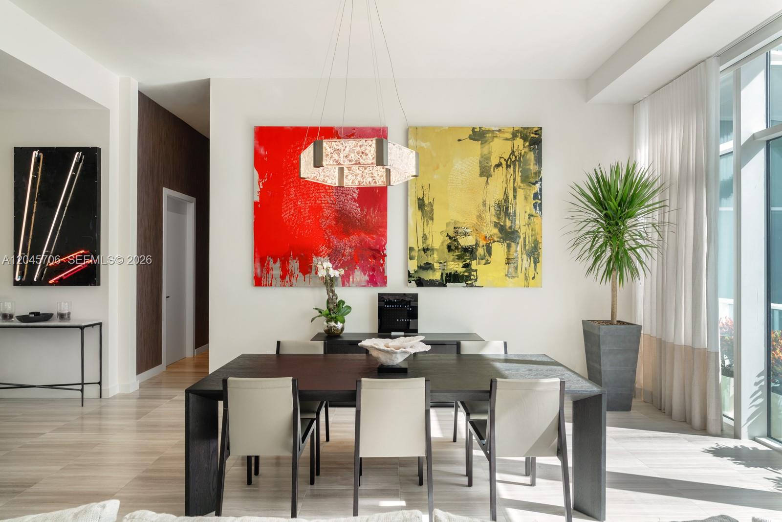 A modern dining room features a dark wood table, abstract art, and a geometric chandelier — 4701 N Meridian Ave # 209, Miami Beach FL 33140, MIAMI BEACH, FL
