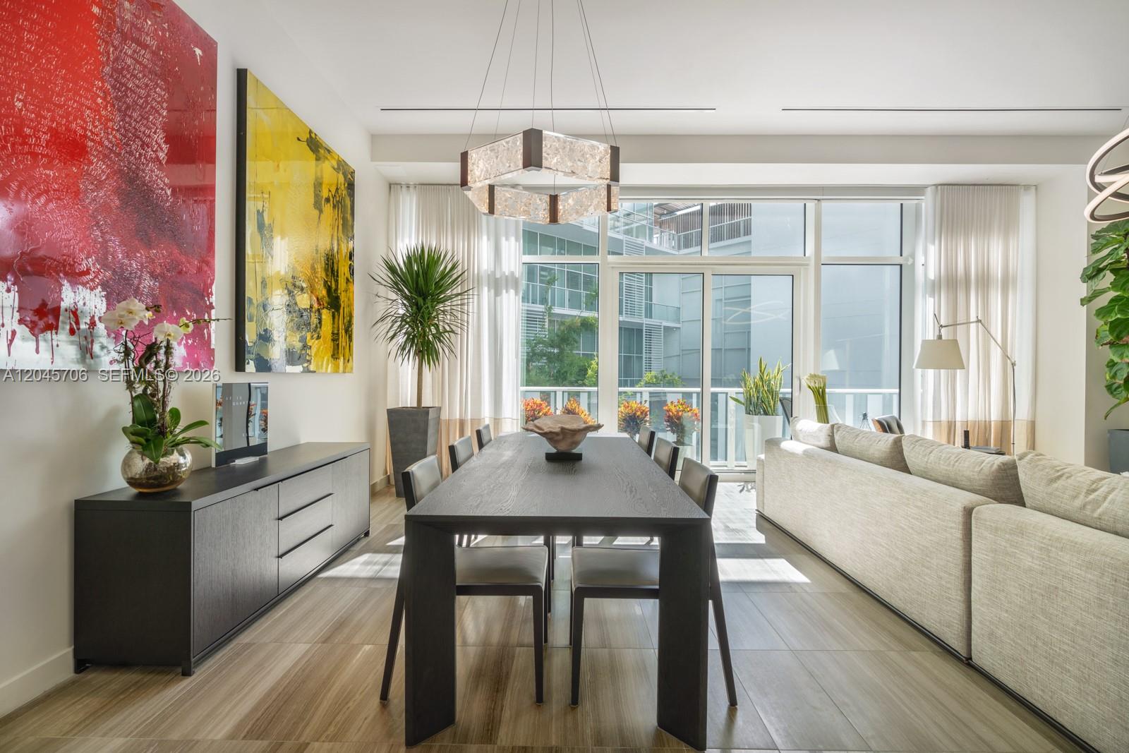 A modern dining room features a dark wood table, contemporary chandelier, and large abstract art — 4701 N Meridian Ave # 209, Miami Beach FL 33140, MIAMI BEACH, FL