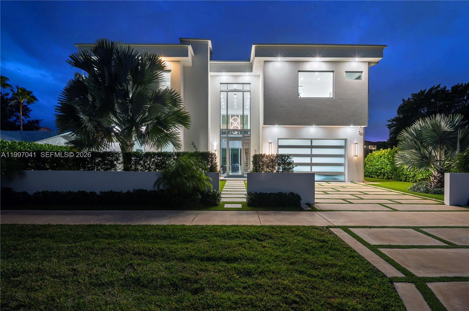 A modern two-story house features a glass entryway, a multi-car garage, and a paved driveway — 2628 Marcinski Rd, Jupiter FL 33477, JUPITER, FL