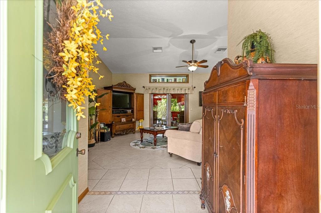 A view from a doorway into a living room with tile floors and wooden furniture — 2964 S CYGNET TERRACE, INVERNESS, FL