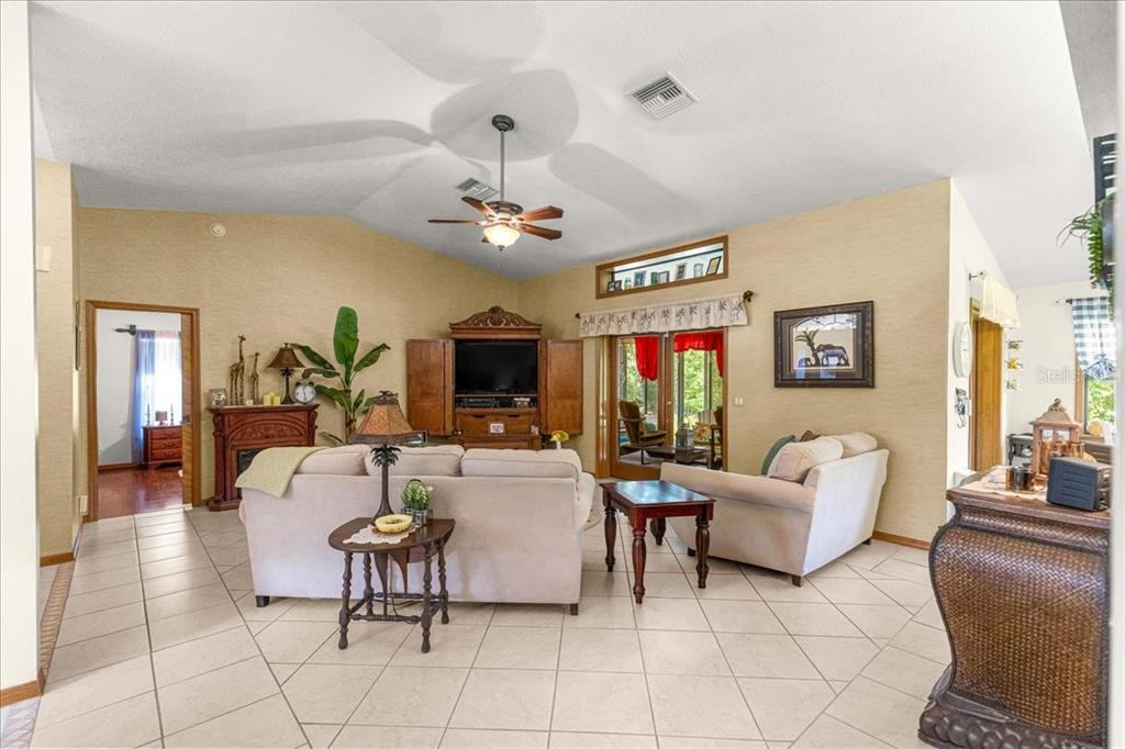 A living room with beige walls, tile flooring, a vaulted ceiling, and two light-colored sofas — 2964 S CYGNET TERRACE, INVERNESS, FL