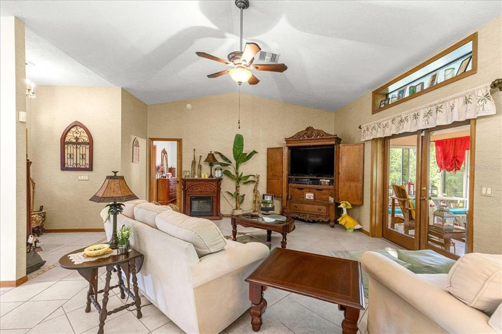 A living room features a vaulted ceiling, tile flooring, a fireplace, and a large entertainment center — 2964 S CYGNET TERRACE, INVERNESS, FL