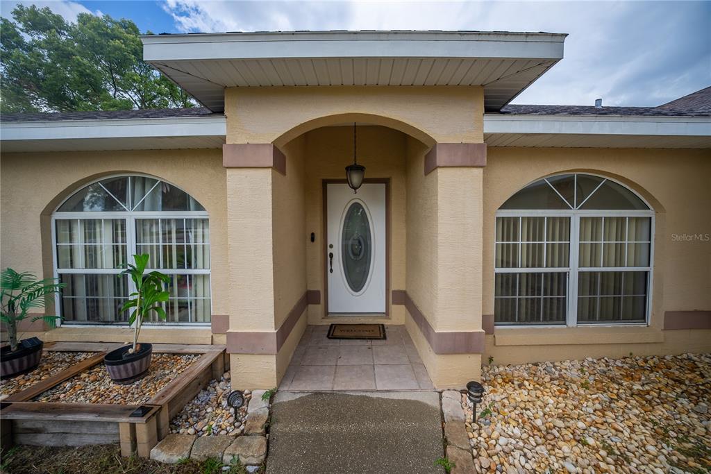 The exterior of a house features a covered entryway with an arched doorway and windows — 6310 SW 82ND PLACE, OCALA, FL