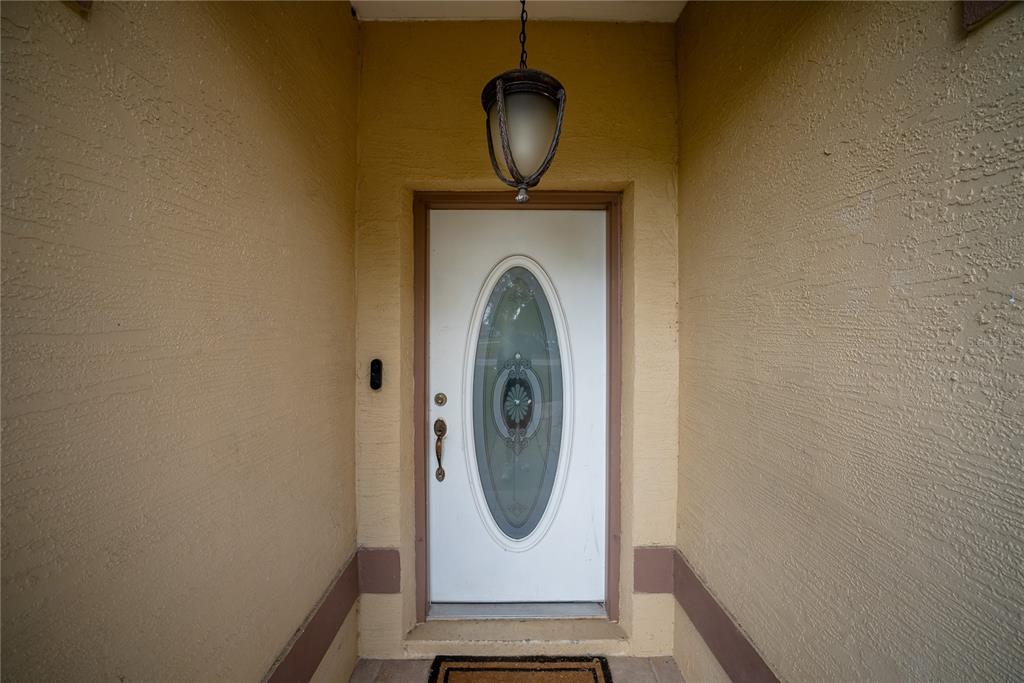 A white front door with an oval glass insert is set within a stucco entryway — 6310 SW 82ND PLACE, OCALA, FL