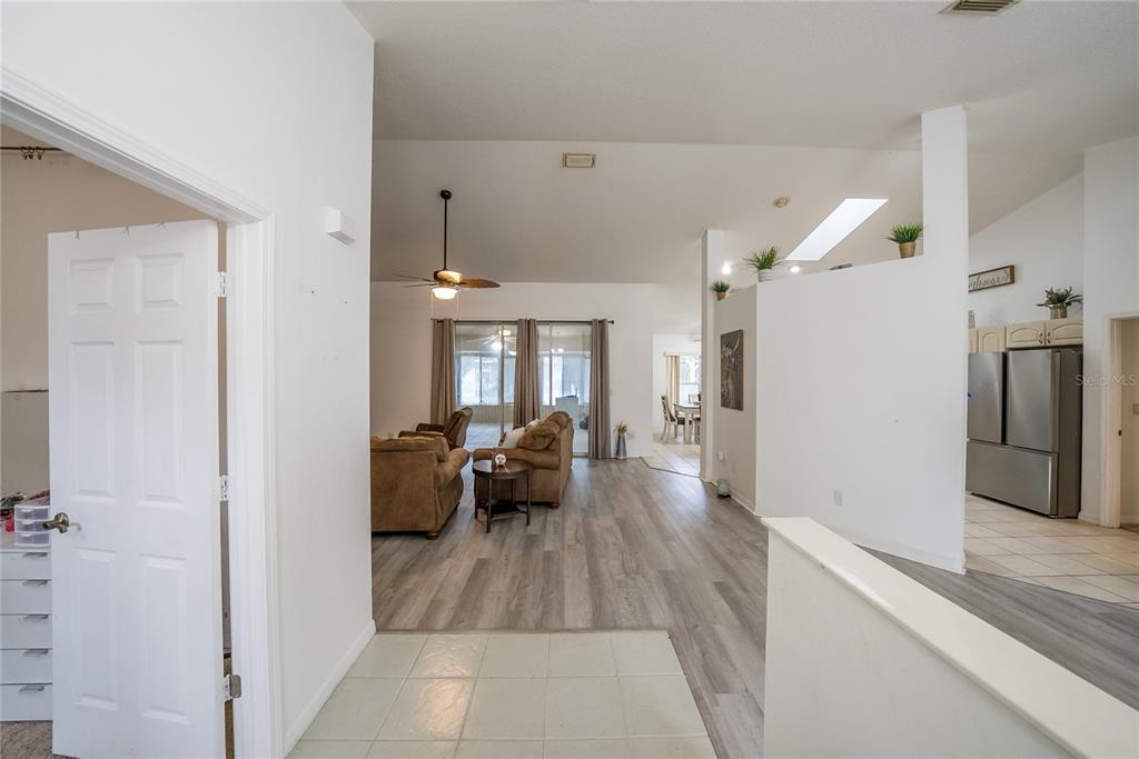 An interior view shows a tiled entryway leading to a living area with wood-look flooring — 6310 SW 82ND PLACE, OCALA, FL