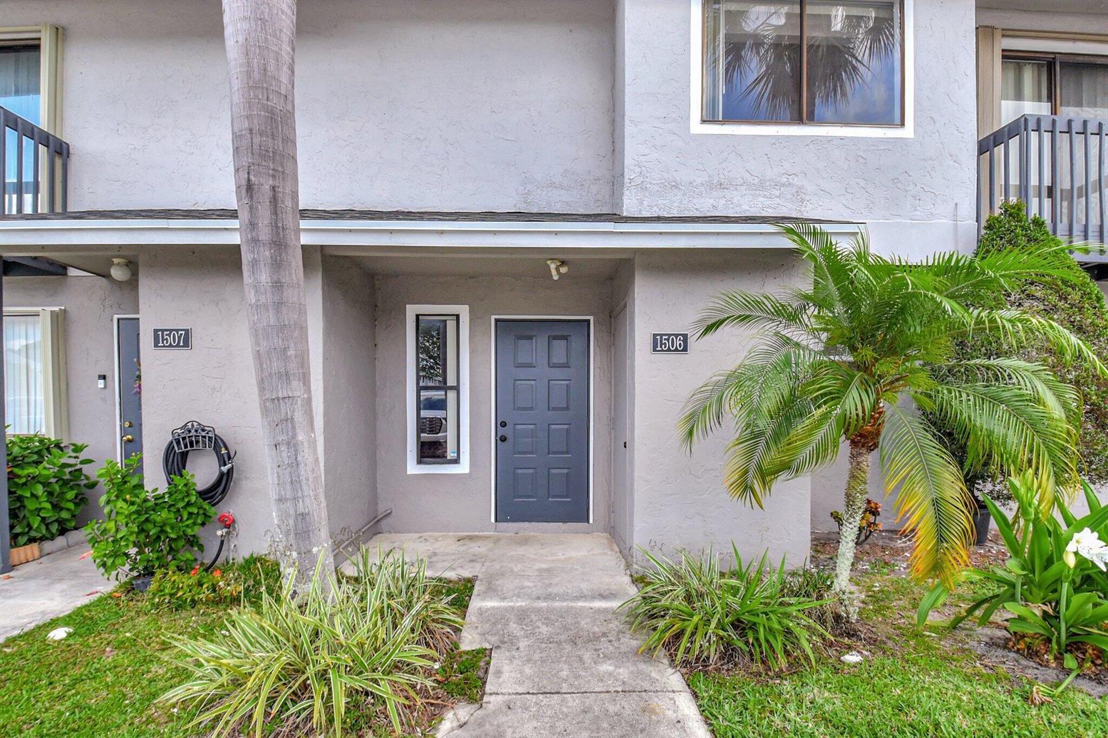 The exterior of a two-story residential building features gray stucco walls and a gray front door — 1506 Wharf Lane, FL 33463, FL