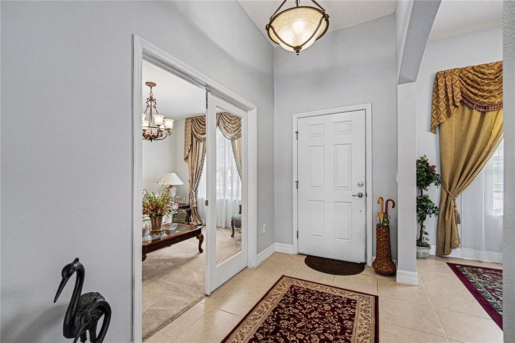 A tiled entryway features a white front door, a glass-paneled doorway, and a decorative rug — 1025 MORGAN CIRCLE NE, PALM BAY, FL