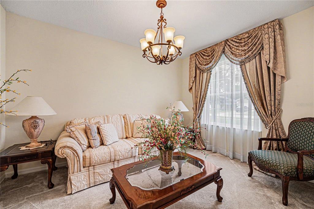 A living room features a beige sofa, a wooden coffee table, and ornate window drapes — 1025 MORGAN CIRCLE NE, PALM BAY, FL