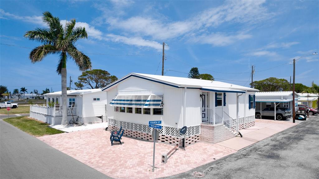 A white manufactured home with a brick-patterned base and a paved patio area — 10315 CORTEZ ROAD W UNIT 1-4, BRADENTON, FL