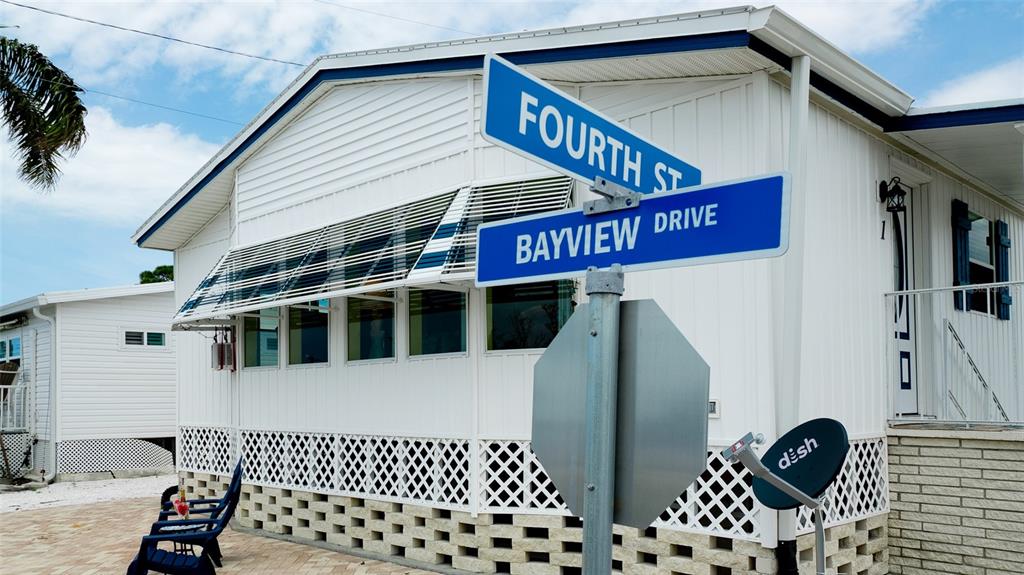 A white mobile home exterior features a street sign intersection and a satellite dish — 10315 CORTEZ ROAD W UNIT 1-4, BRADENTON, FL