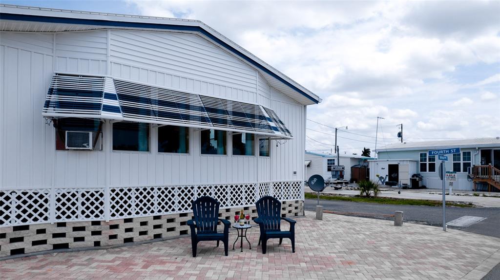 A white mobile home exterior features a paved patio with two chairs and an awning — 10315 CORTEZ ROAD W UNIT 1-4, BRADENTON, FL