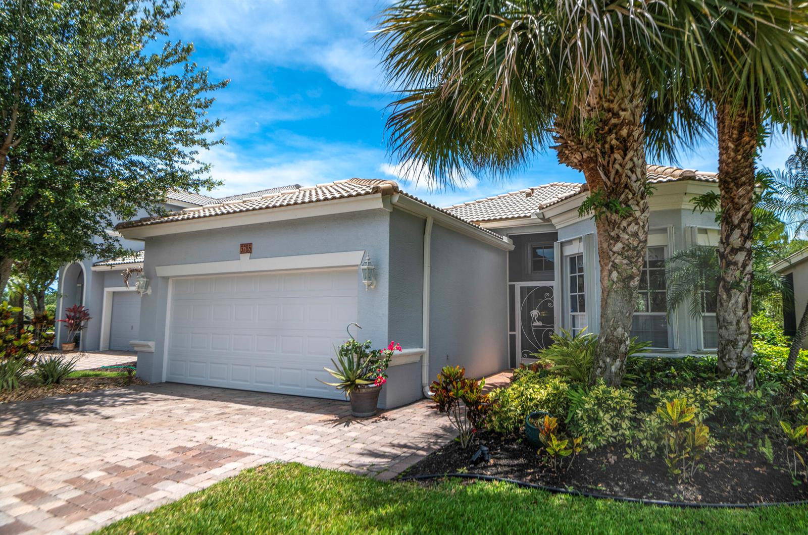 A single-story house with a light gray exterior, a two-car garage, and a palm tree — 3785 NW Deer Oak Drive, Jensen Beach FL 34957, JENSEN BEACH, FL