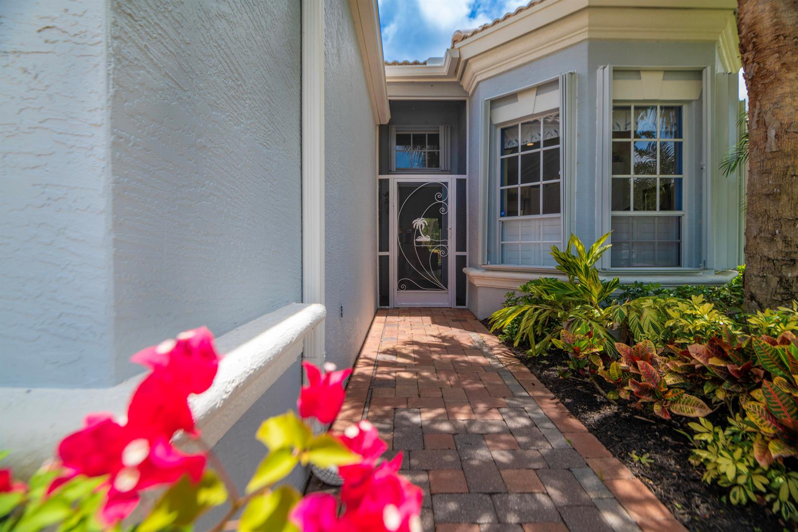 A brick walkway leads to a front entrance with a decorative screen door — 3785 NW Deer Oak Drive, Jensen Beach FL 34957, JENSEN BEACH, FL