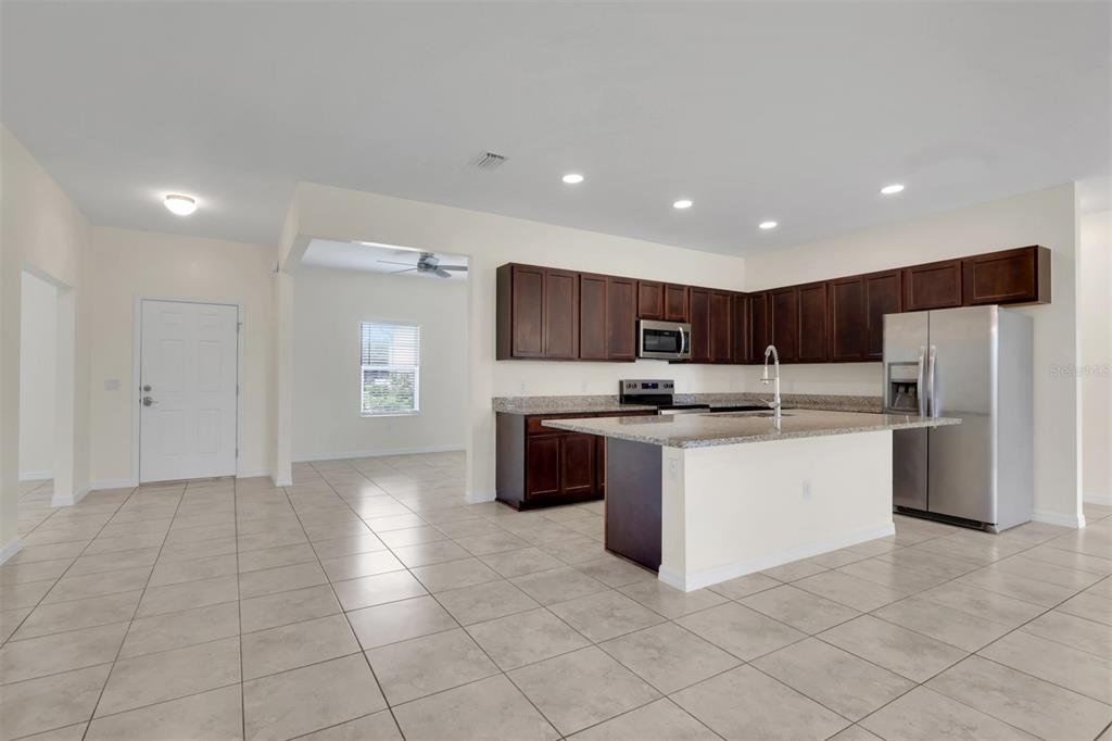 A kitchen with dark wood cabinets, granite countertops, and a central island with tile flooring — 25108 PALISADE ROAD, PUNTA GORDA, FL