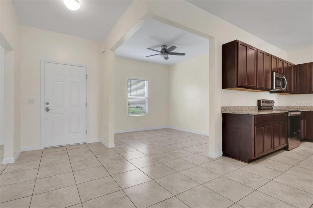 An open-concept kitchen and dining area features dark wood cabinets, granite countertops, and tile flooring — 25108 PALISADE ROAD, PUNTA GORDA, FL