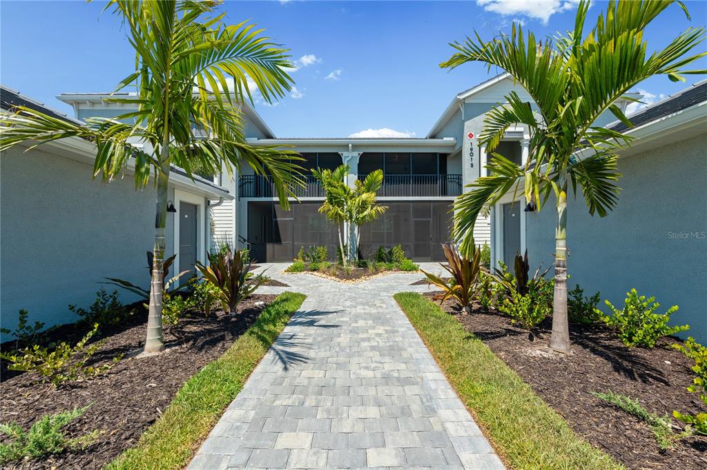 A paved walkway leads to the entrance of a two-story building with palm trees — 19015 SCALLOP LOOP UNIT 103, LAKEWOOD RANCH, FL