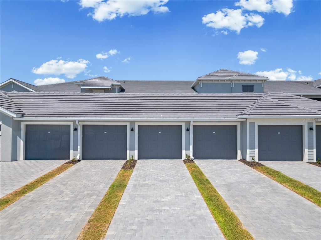 A row of five gray garage doors with paved driveways and grass strips — 19015 SCALLOP LOOP UNIT 103, LAKEWOOD RANCH, FL