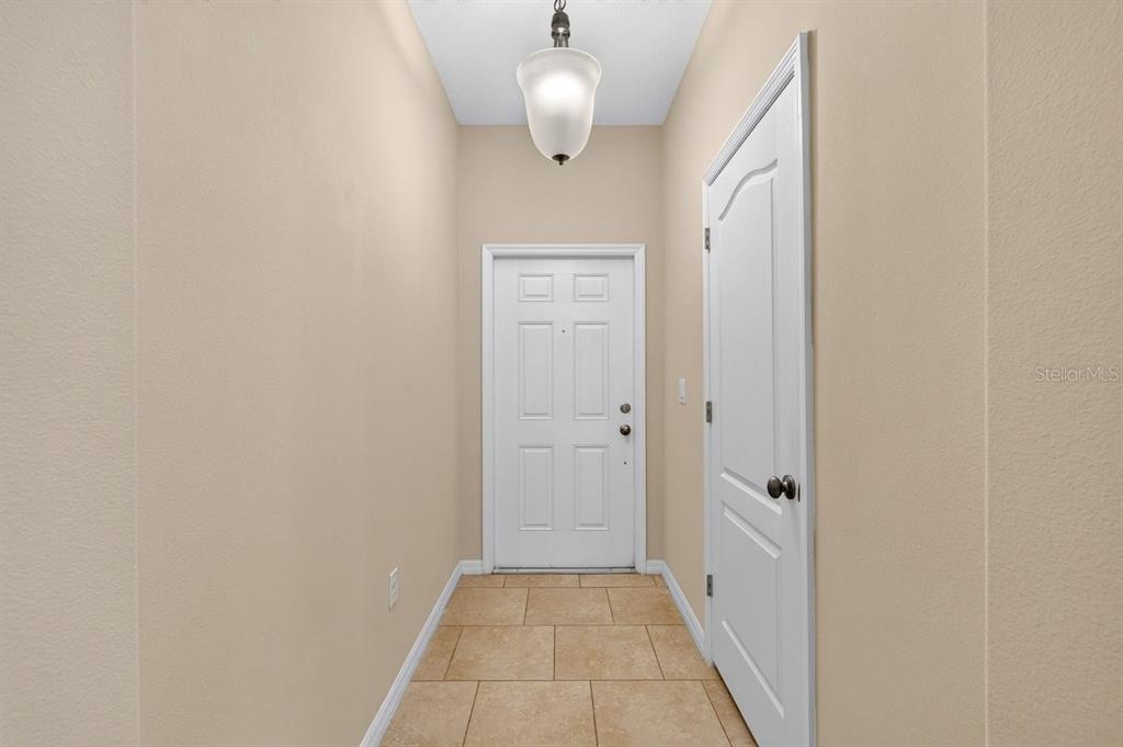 An entryway features a white front door, a side door, and tile flooring — 205 WENTWORTH GRANDE DRIVE, DAYTONA BEACH, FL